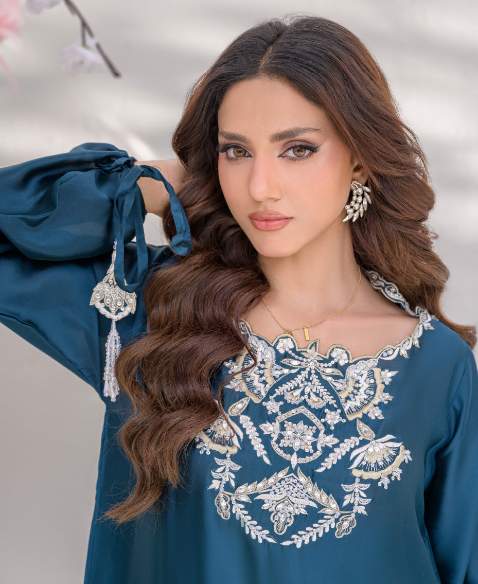 Teal sheesha silk long shirt with gold kora dabka embroidery on neckline, paired with wide-leg pants, featuring pearl and gold tassels for a luxurious festive look.